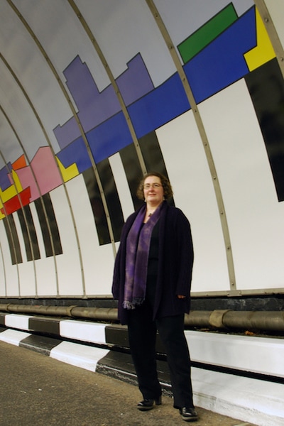 The artist, Ali Barker, next to the Liverpool Composition skyline mural installed in the Birkenhead Tunnel